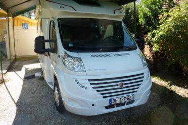 Camping-car blanc garé sous abri.