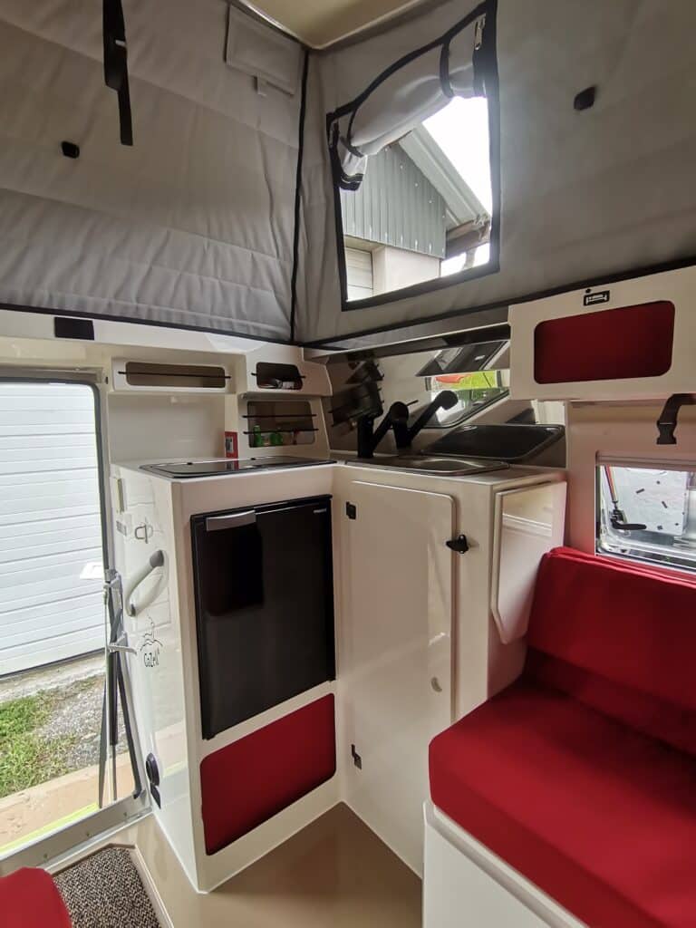 Intérieur d'une caravane moderne avec sièges rouges.