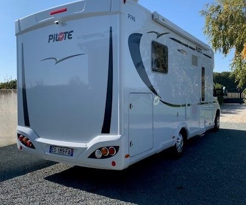 Camping-car blanc stationné en plein air.