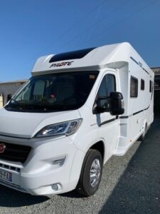 Camping-car blanc garé sous le soleil.