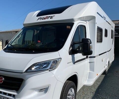 Camping-car blanc garé sous le soleil.