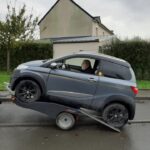 Voiture sur remorque tractée par camping-car.