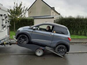 Voiture sur remorque tractée par camping-car.