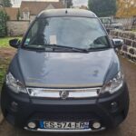Voiture microcar stationnée dans une allée résidentielle.