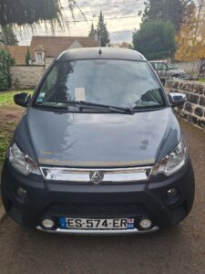 Voiture microcar stationnée dans une allée résidentielle.