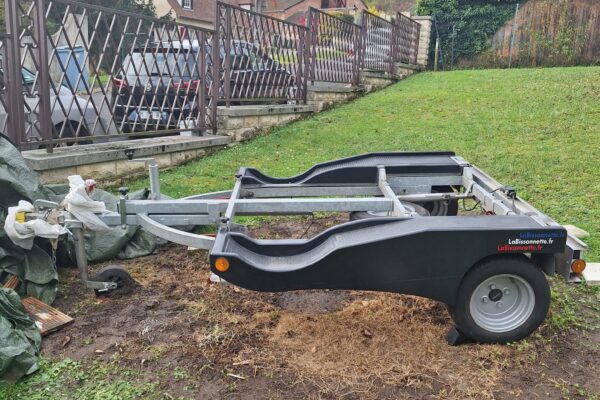 Leerer Anhänger auf Rasen in der Nähe eines Zauns.