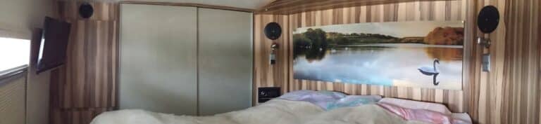Intérieur d'une caravane avec lit et télévision.