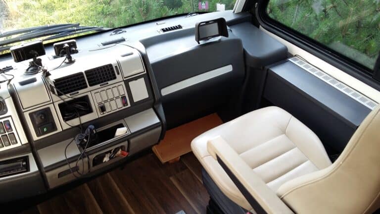 Intérieur cabine camion avec siège et instruments.