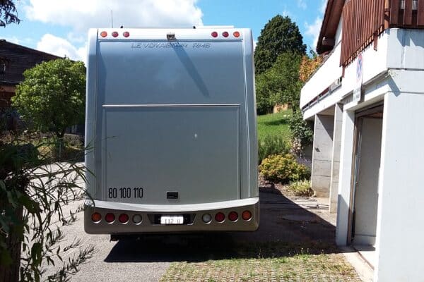 Wohnmobil vor einem sonnigen Gebäude geparkt.