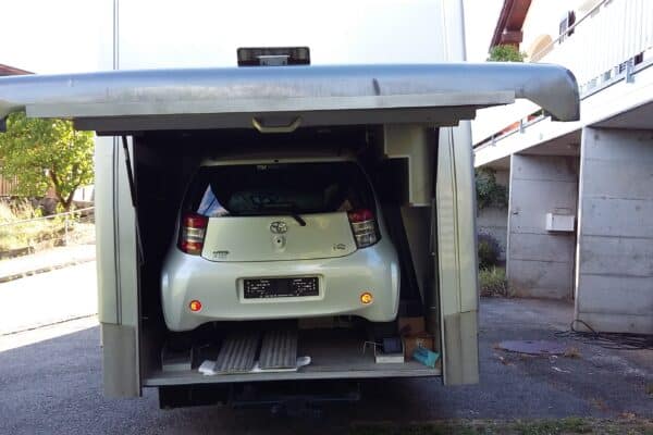 Weißer Wagen, der in einen LKW Transporter geladen wurde