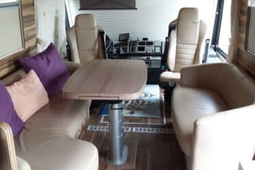 Innenansicht eines komfortablen Wohnmobil mit Tisch und Sitzen.