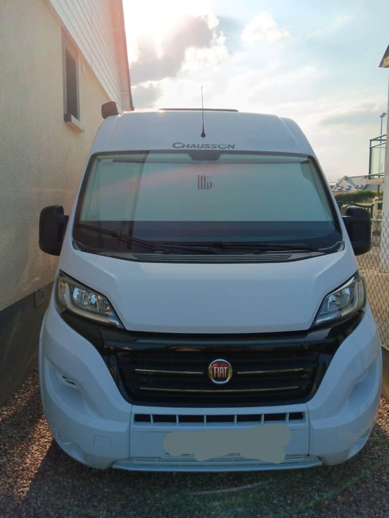 Camping-car Chausson blanc stationné devant maison