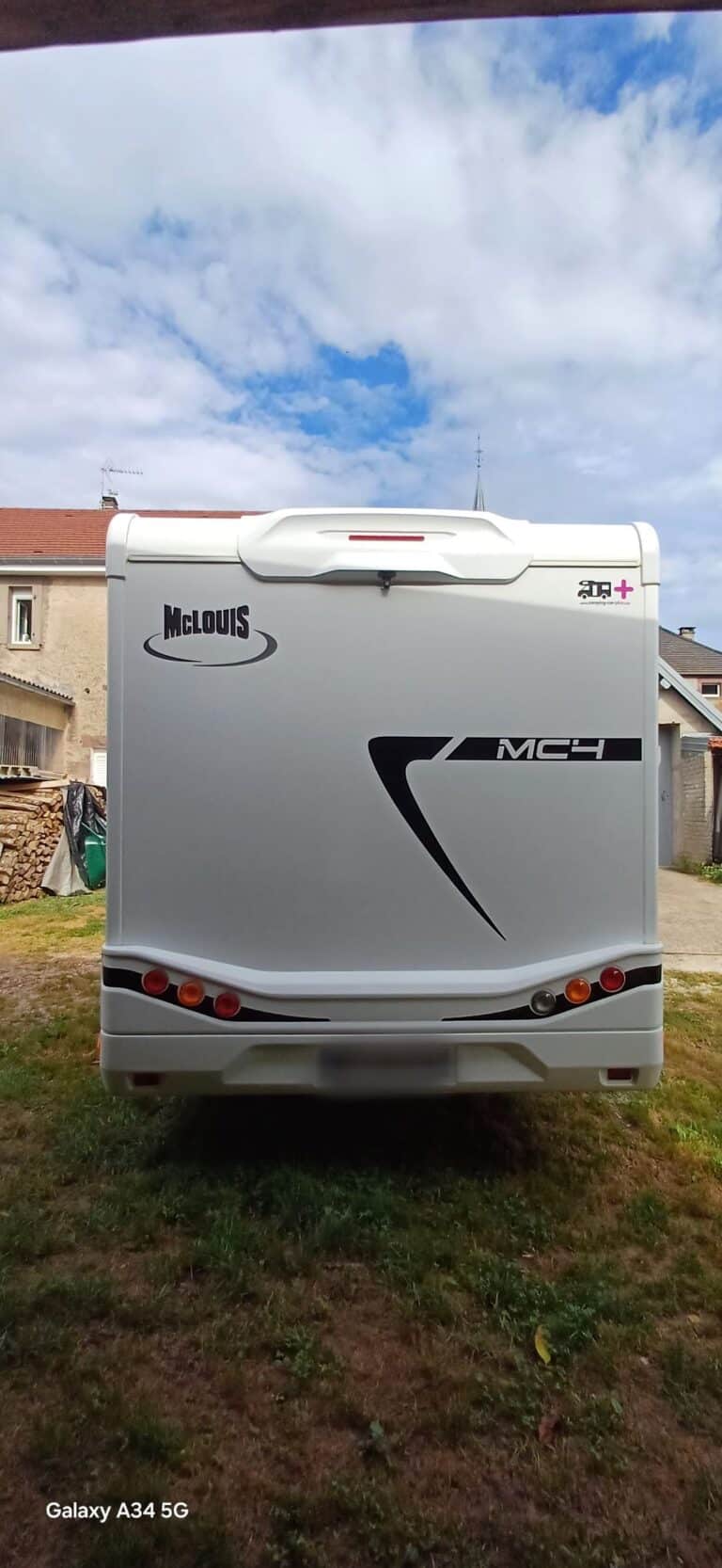 Arrière d'un camping-car McLouis blanc sous ciel nuageux