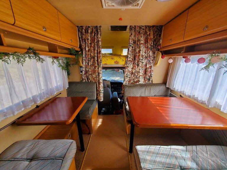 Intérieur cosy de camping-car avec banquettes et tables