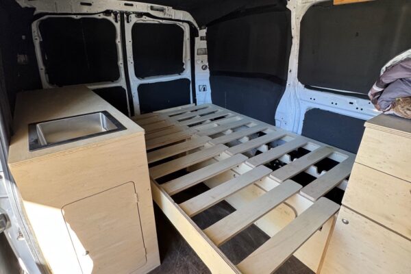 Intérieur de camionnette aménagée avec lit et rangements