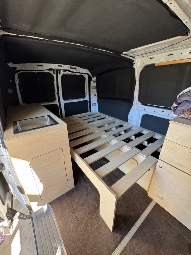 Intérieur de camionnette aménagée avec lit et rangements