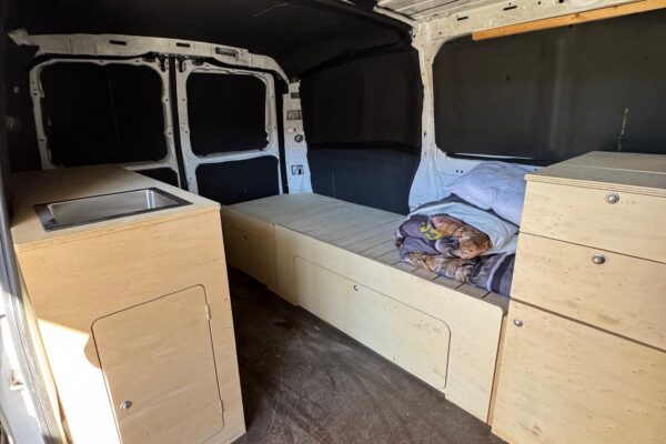 Intérieur de fourgon aménagé avec lit et rangements en bois