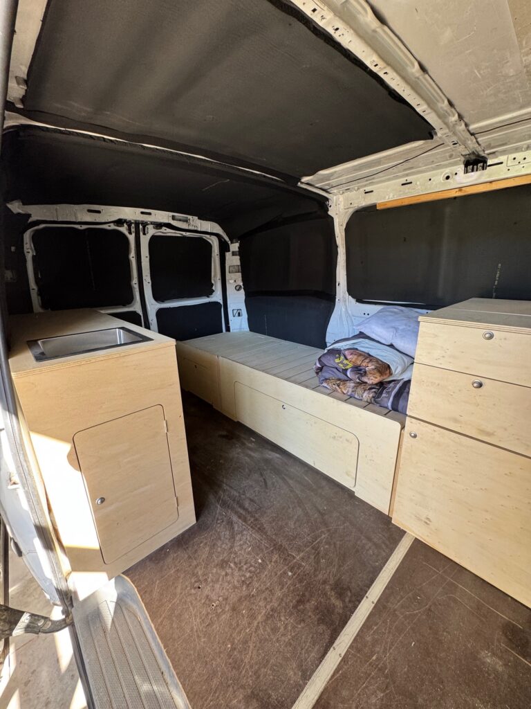 Intérieur de fourgon aménagé avec lit et rangements en bois