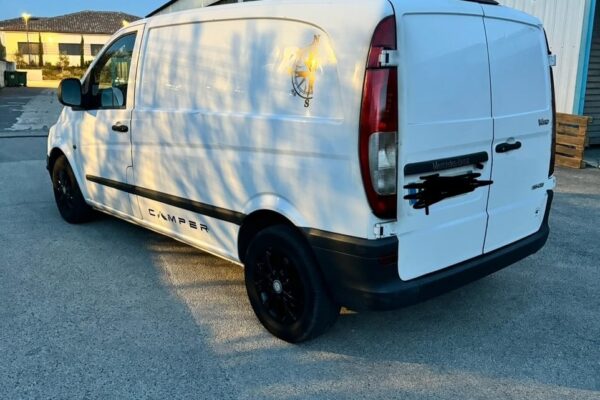 Fourgon blanc Mercedes stationné devant un bâtiment industriel