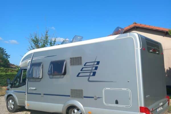 Camping-car gris stationné sous ciel bleu