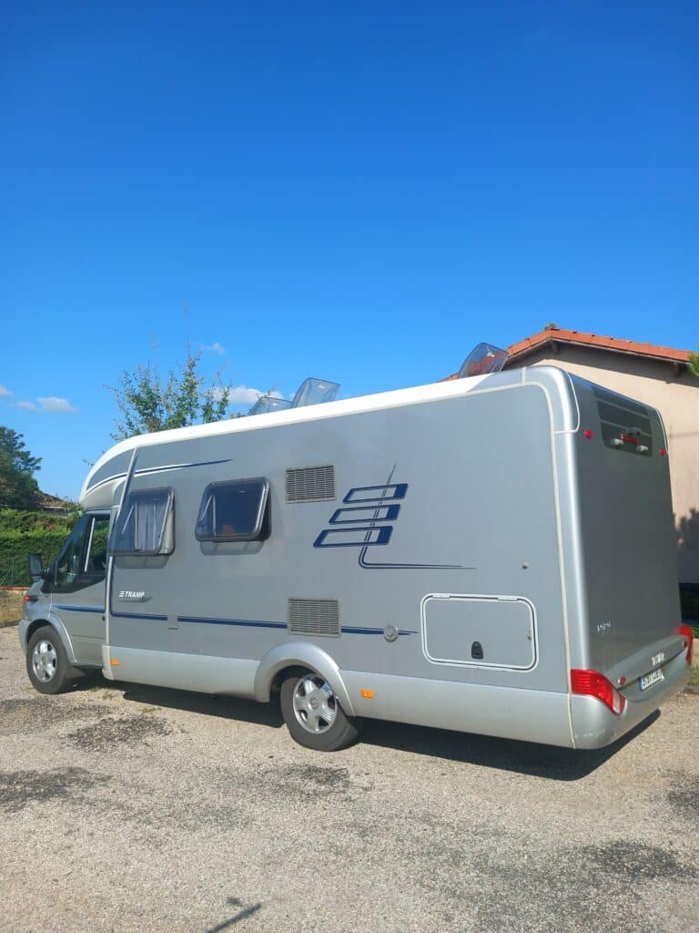 Camping-car gris stationné sous ciel bleu