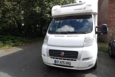 Camping-car Rapido blanc garé près d'une maison