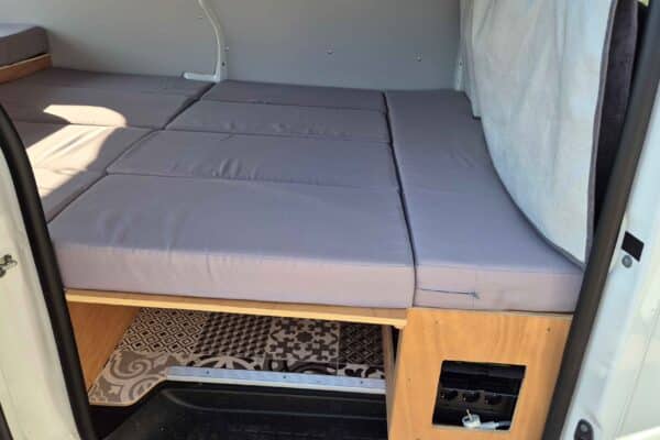 Innenausstattung eines Campervans mit Doppelbett und Stauraum