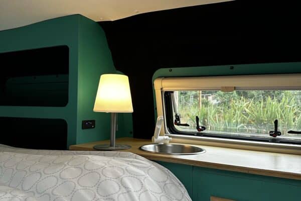 Gemütliches Interieur von Wohnmobil mit Bett und Lampe