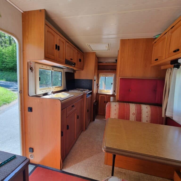 Intérieur boisé de camping-car avec cuisine et coin repas