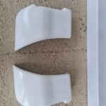 Deux pièces de plastique blanche sur sol en béton.