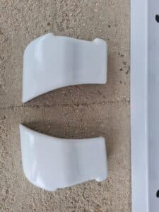 Deux pièces de plastique blanche sur sol en béton.