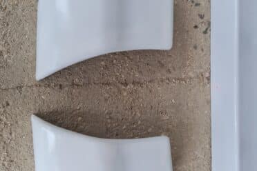 Deux pièces de plastique blanche sur sol en béton.