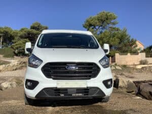 Fourgonnette Ford blanche stationnée en bord de mer