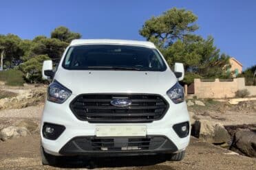 Fourgonnette Ford blanche stationnée en bord de mer