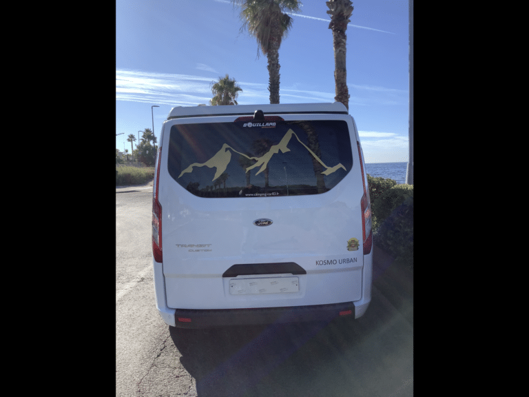 Fourgon blanc Ford Transit stationné face à la mer
